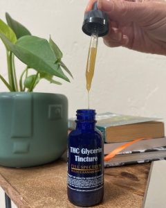 THC Glycerin Tincture Chronic Health THC Glycerin Tincture dripping on nightstand plant books Halo Infusions