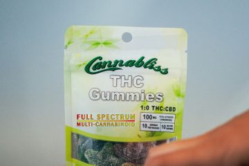 Elevate Your High THC Gummies and a hand reaching for them. Tucson edibles